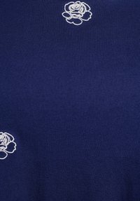 Námořnická modrá látka s bílými vyšívanými vzory růží. Materiál vypadá jemně a má hladkou texturu, která vykazuje konzistentní pletený vzor.