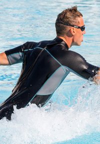 Zwart wetsuit met lichtblauwe accenten, slim fit ontwerp, korte mouwen en een hoge kraag, gedragen door een zwemmer die met water spettert.
