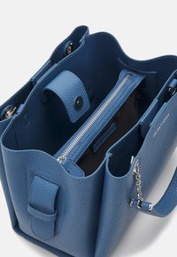 Modrá texturovaná kožená kabelka se zipovou kapsou a dvěma přihrádkami. Má magnetické zapínání a stříbrný akcent.