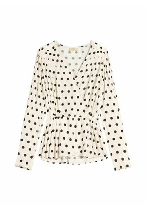 Biała bluzka zapinana na kopertę z długimi rękawami, czarne kropki, plisowany pas i dekolt w kształcie litery V.