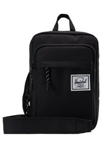 Czarna torebka na ramię z tkaniny o prostokątnym kształcie, z zamykanymi na zamek komorami, przednią kieszenią oraz górnym uchwytem. Posiada naszywkę z logo.