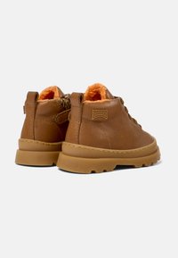 Bottines en cuir marron avec une surface texturée, semelles en caoutchouc et doublure en polaire orange. Présente un logo et une fermeture éclair d'un côté.