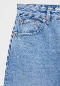 Jean en denim bleu clair avec une taille haute, des rivets en cuivre et une petite poche avant. Tissu texturé avec un motif tissé classique.