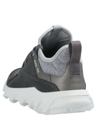 Grauer Sportschuh mit einem Obermaterial aus glattem Leder und strukturiertem Stoff, gepolstertem Schaft und einer weißen Gummisohle mit ausgeprägtem Profil.