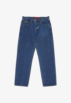 Tmavomodré riflové nohavice s priamym strihom, piatimi vreckami a červenou páskou s logom na páse. Výrazné šitie po celej dĺžke.