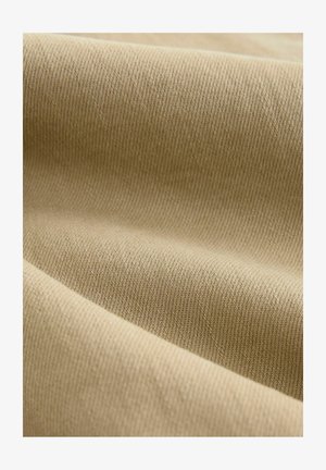 Kreemikas kangas, millel on sile ja tekstureeritud pind, diagonaalsed ribid ja peen sära. Materjal on pehme ja paindlik.