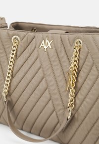 Sac à main en cuir taupe matelassé avec des poignées en chaîne dorée et un emblème AX à l'avant.