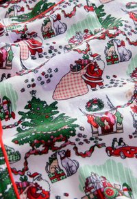 Bombažna tkanina z božičnim vzorcem, ki vključuje Miklavža, božične drevesce, darila in hišne ljubljenčke v rdeči, zeleni in beli barvi. Teksturna površina.