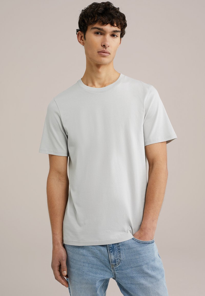 Tricou gri cu mânecă scurtă și decolteu rotund, fabricat dintr-un material moale din bumbac. Asortat cu blugi albaștri deschiși, cu o croială lejeră.