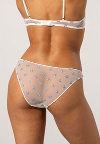 Lacevit set med vit underkläder med blå broderade blommor, som har ett transparent tyg och en figursydd passform. Remmar och midjeband i matchande vitt.