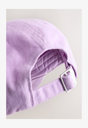 Bawełniana czapka bejsbolowa w kolorze bzu, z metalową klamrą do zapinania i przeszyciami na górze. Wnętrze pokazuje podszewkę o fakturze podkreślającej trwałość.