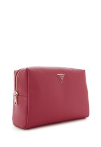 Roze synthetische pouch met een gladde textuur, rechthoekige vorm, gouden hardware en een driehoekig logo aan de voorkant. Rits sluiting.