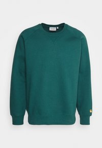 Sudadera verde de cuello redondo hecha de un tejido suave, con puños y dobladillo de canalé, y un pequeño logo en la manga izquierda.