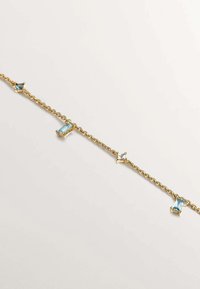 Pulsera de cadena de oro con gemas rectangulares azules y transparentes alternadas, que presenta un delicado diseño de eslabones retorcidos. Textura suave.