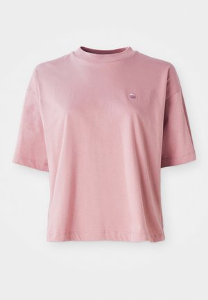 Camiseta de cuello redondo de manga corta en rosa claro con un pequeño logo en la parte superior izquierda del pecho, exhibida sobre un fondo blanco.
