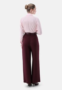 Light pink blouse with a collar, paired with burgundy wide-leg trousers, featuring a fitted waistband and concealed pockets.