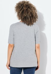 Camiseta gris de manga corta hecha de una tela suave. Presenta un corte holgado y un escote redondo, con una textura suave y un detalle mínimo.