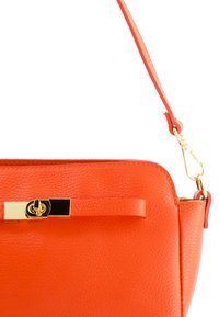 Orange Lederhandtasche mit glatter Textur, abnehmbarem Schulterriemen, goldenen Beschlägen und einem Verschluss mit einem eleganten Design.