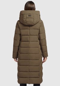 Garš brūns pūkains mētelis ar izšūtu dizainu, liela kapuce un elastīgas aproces. Iekļauj aizmugurēju logo uzlīmi un sānu kabatas. Gluda tekstūra.