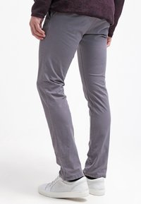 Slim-fit, šedé bavlněné chinos s hladkou texturou. Má středně vysoký pas a boční kapsy. Spárováno s bílými teniskami.