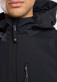 Black waterproof jacket featuring a zippered front, adjustable hood, and textured fabric with visible stitching and drawstring accents.