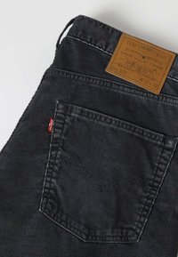 Μαύρο τζιν Levi's που δείχνει πίσω τσέπη με την κόκκινη ταμπέλα Levi's και καφέ δερμάτινο λογότυπο με μέγεθος W32 L32.