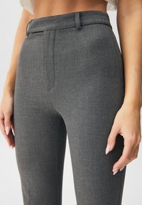 Grijze op maat gemaakte broek van textuurstof, met een platte voorkant, ceintuurlussen en zijzakken. Het slim fit ontwerp accentueert de vorm.