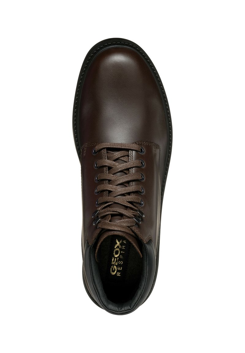 Bota de cuero marrón hasta el tobillo con puntera redonda, ojales reforzados y cordones marrones. Presenta un cuello de cuero negro y un suave forro interior.