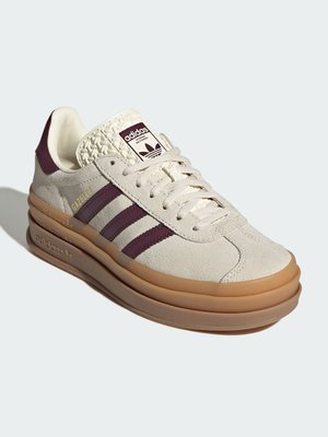 Baskets Adidas Gazelle beige avec des bandes marron, languette crème texturée, semelle en gomme et marquage doré "Gazelle" sur le côté.