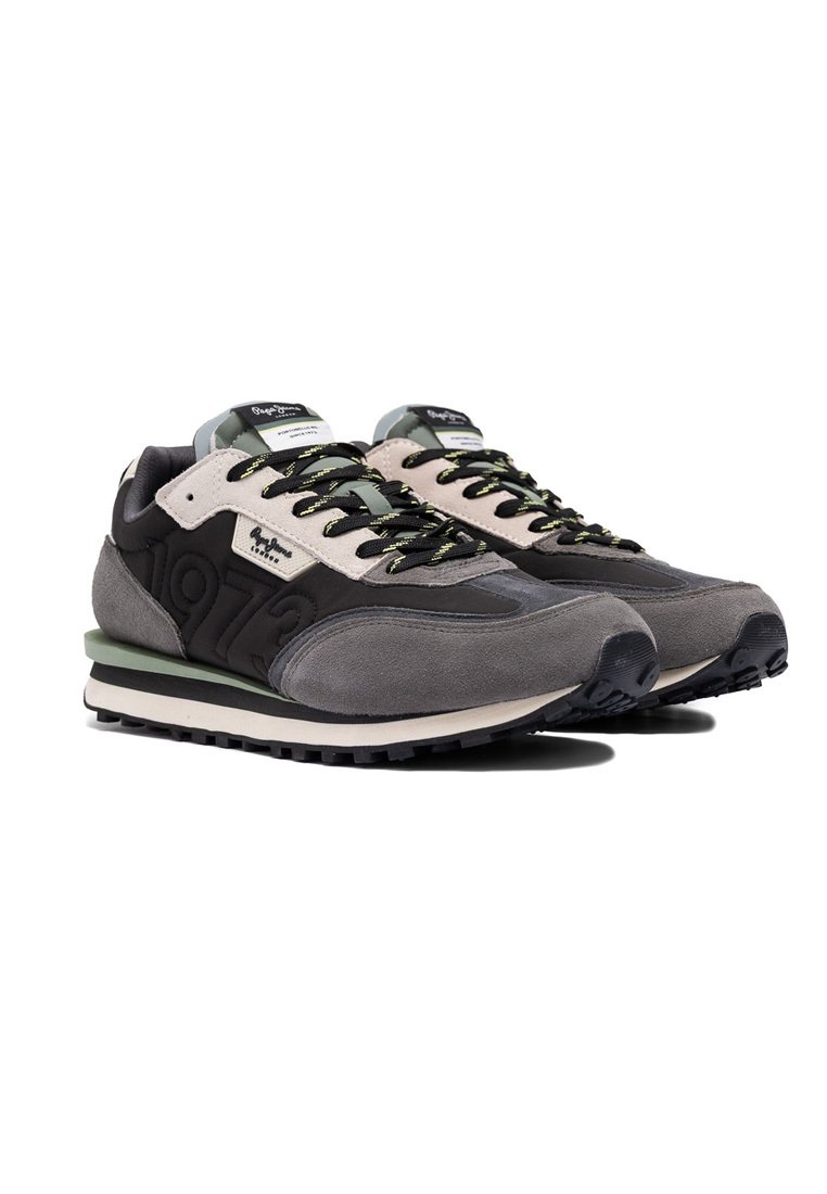 Para szarych i czarnych casualowych sneakersów z zielonymi akcentami, czarnymi sznurówkami i wytłoczonym napisem "1973" z boku, wyeksponowana na białym tle.