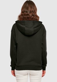 Svart huva sweatshirt med avslappnad passform, ribbade muddarna och nederkant, samt ett strukturerat tyg. Synlig huva bak.