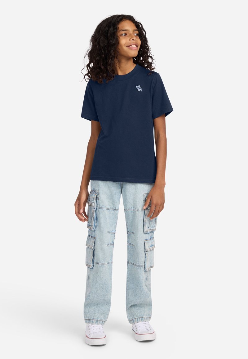 Navy cotton t-shirt with short sleeves, featuring a small white logo. Paired with light blue cargo jeans with multiple pockets and a relaxed fit.