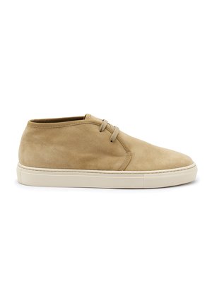 Stivaletti beige in suede fino alla caviglia con punta arrotondata, due occhielli e suola in gomma crema. Presentano una texture liscia e un design minimalista.