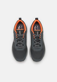 Scarpe da atletica grigie in rete con dettagli arancioni, design con lacci e suole imbottite, adatte per un uso attivo. Materiale leggero e traspirante.