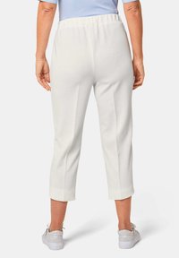 Witte cropped broeken van een textuurstof, met een elastische tailleband en zijnaad, gecombineerd met zilveren sneakers.