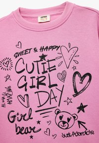 Roze katoenen sweatshirt met zwarte grafische tekst en krabbels, waaronder harten, sterren en een beerillustratie. Verstelbare halslijn.