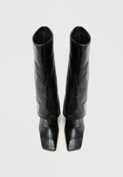 Čierne kožené čižmy po kolená s lesklou textúrou, špicatou špičkou a priliehavým strihom zúženým na vrchu.