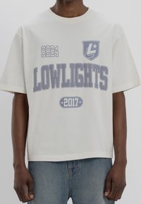 Bílý bavlněný tričko s grafikou "LOWLIGHTS" v světle šedé barvě. Obsahuje texty "SS24" a "2017", krátké rukávy a volný střih.