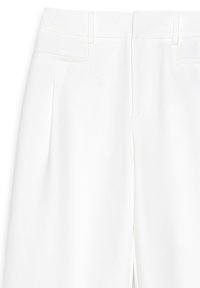 Białe dopasowane spodnie o gładkiej fakturze, z fałdami z przodu, bocznymi kieszeniami i płaskim paskiem w talii. Klasyczny, czysty design.