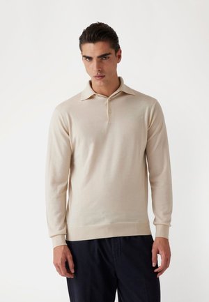 Polo shirt bej cu mânecă lungă, confecționat dintr-un material moale, având un guler clasic și închidere cu trei butoane, cu manșete și tiv cu bandă. 