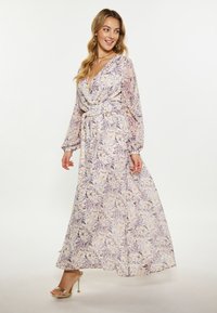 Lange bloemenjurk met een wrap ontwerp, v-hals en vloeiende mouwen. Zachte stof in pastelkleuren met een strik taille en een licht uitlopende rok.