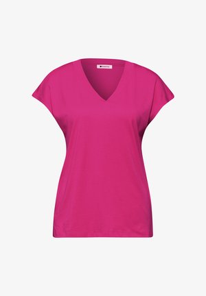 Jasnoróżowa damska koszulka z krótkim rękawem i dekoltem w serek, o luźnym kroju, z małą metką marki wewnątrz dekoltu.