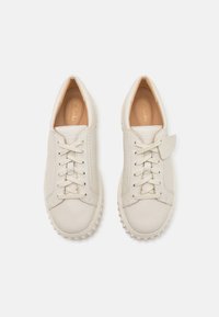 Hvite lær sneakers med runde tær, flate snørebånd og teksturerte gummisåler med prikkete detaljer. Prentet logo på tungen.