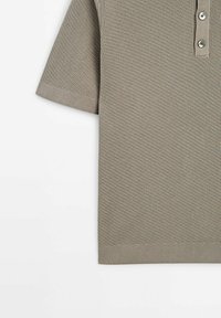 Lyhythihainen poolopaita hillityssä harmaanruskeassa neuloskankaassa, jossa on kolmen napin nappilista ja resorireuna tuomassa rakennetta ja yksityiskohtia.