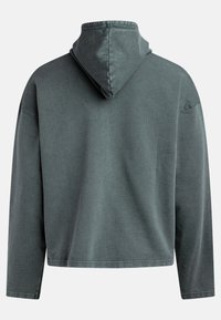 Donkergroene hoodie gemaakt van textiel met structuur. Heeft een relaxte pasvorm, verlaagde schouders en een eenvoudige zoom zonder zichtbare hardware.