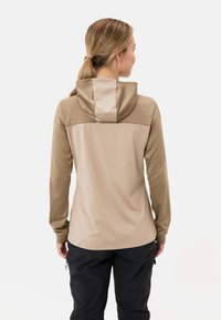 Maglietta a maniche lunghe marrone con cappuccio, caratterizzata da una sezione superiore in contrasto di un marrone chiaro, texture liscia e una vestibilità comoda.