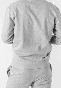 Sudadera gris y pantalones a juego hechos de una tela suave y texturizada. Presenta un ajuste relajado y puños y cintura elásticos.
