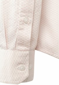 Tela de camisa rosa claro con un patrón geométrico y acentos en blanco y rosa claro, que muestra un puño abotonado y una textura suave.