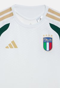 Λευκό αθλητικό πουκάμισο με πράσινες λεπτομέρειες, χρυσό λογότυπο Adidas και κεντημένη κονκάρδα Italia με μπλε, λευκές και κόκκινες ρίγες. Λεπτό υφασμένο ύφασμα.