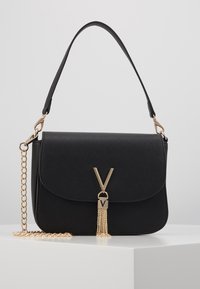 Bolso cruzado negro con un acabado texturizado, herrajes dorados, una correa de cadena y un detalle decorativo de borlas con un cierre de logotipo.
